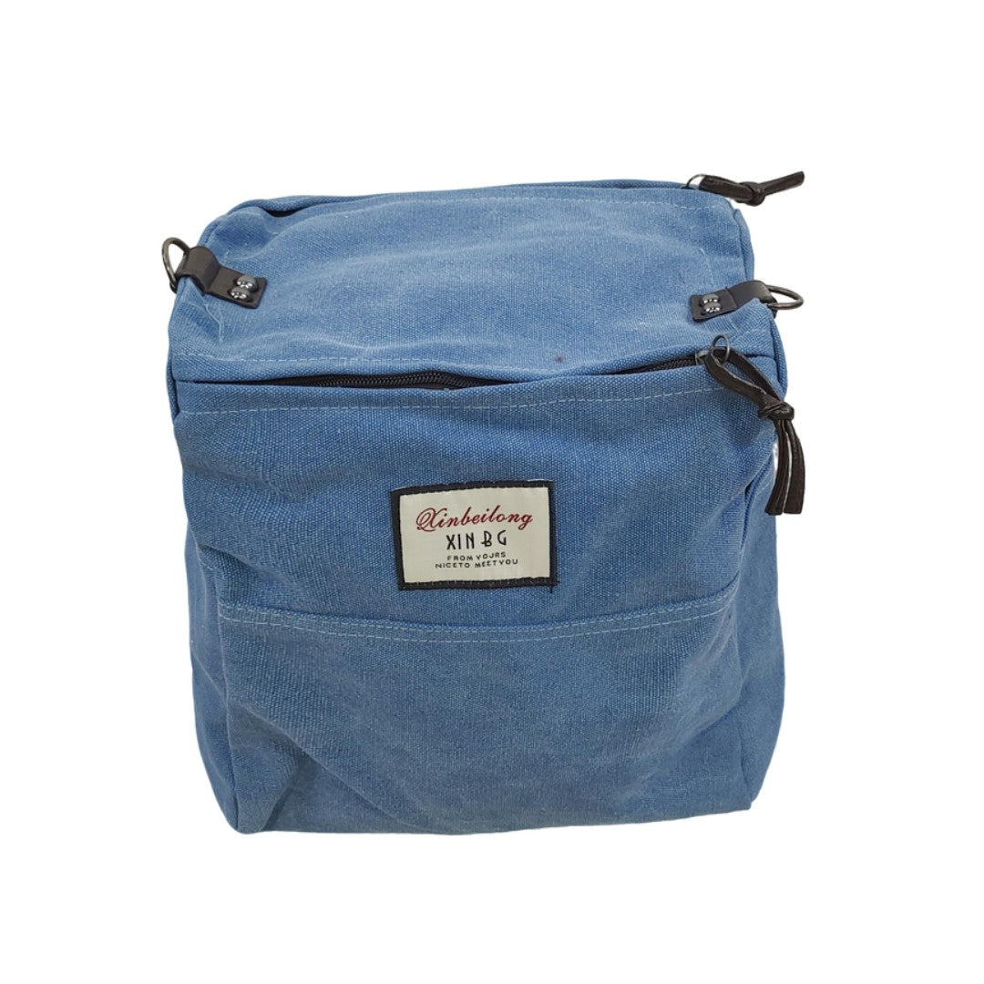 Front view of blue canvas backpack with label and front pocket