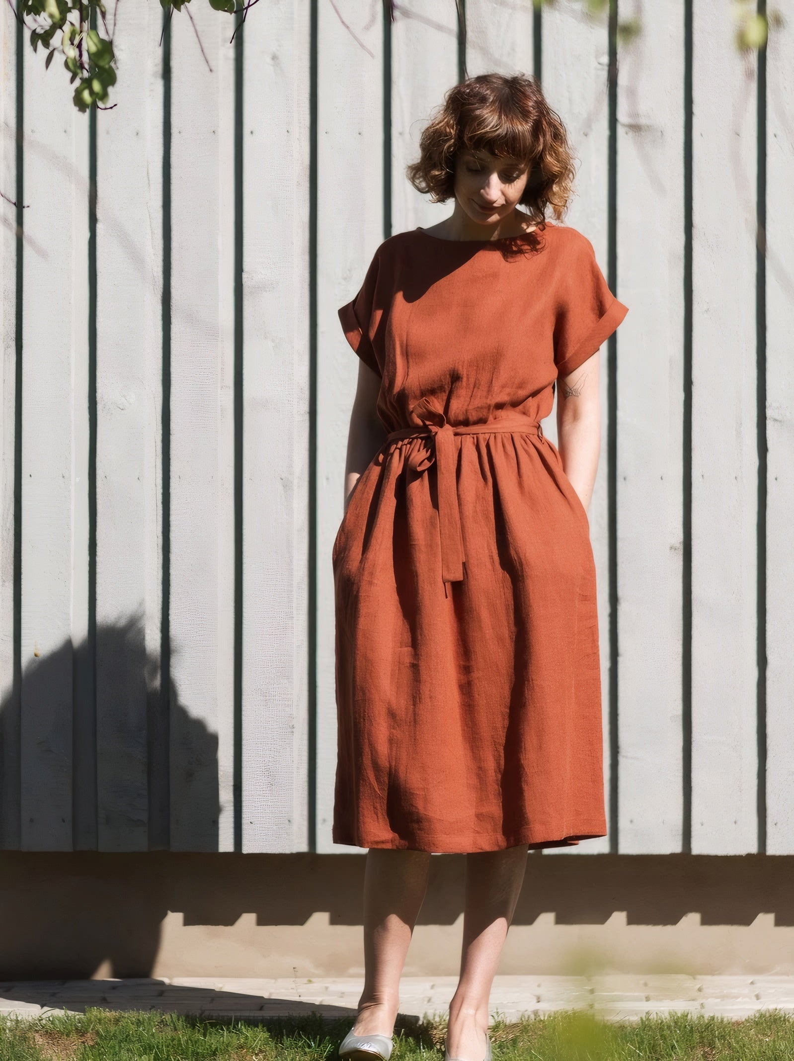 Woman wearing terracotta orange linen midi dress with waist belt