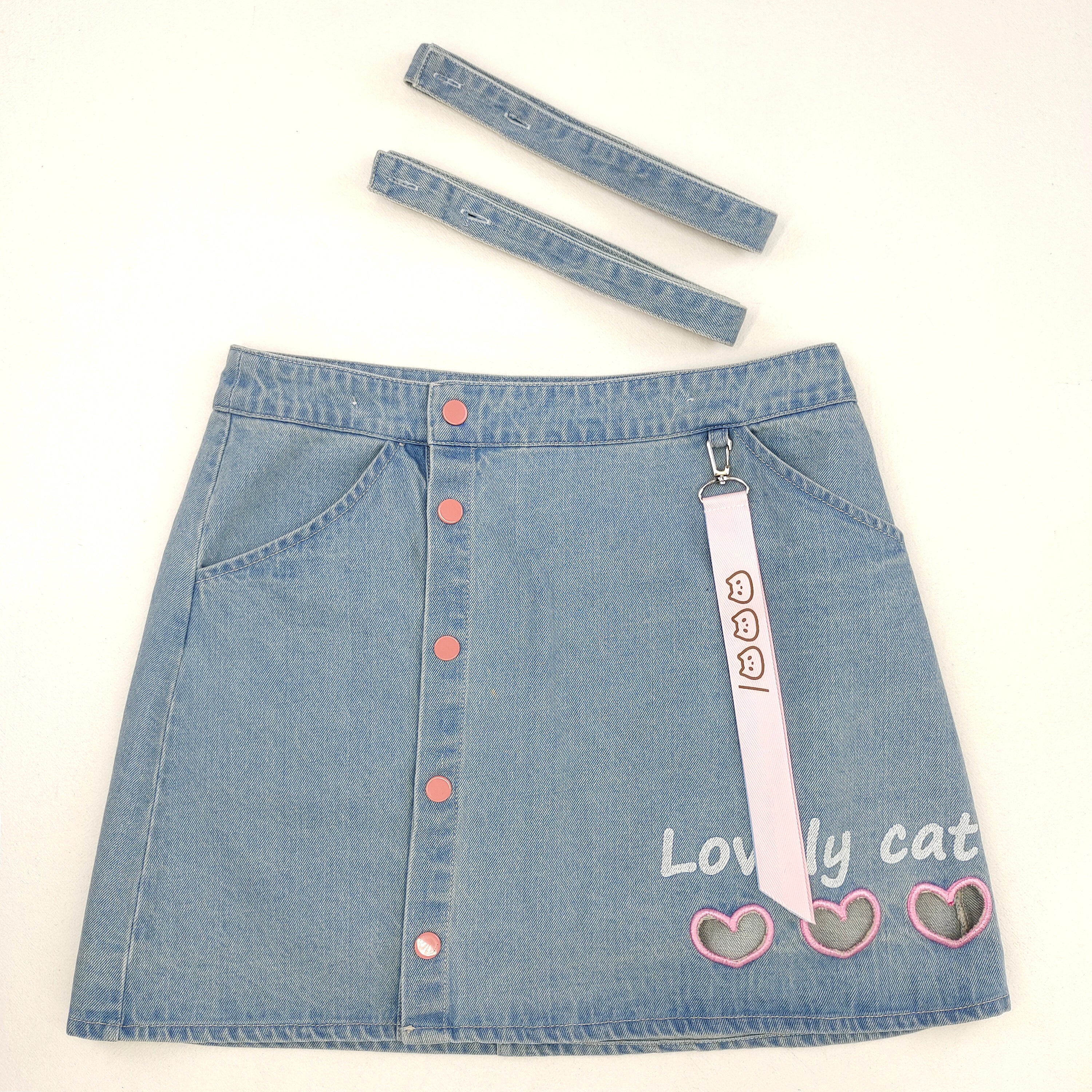 Close-up of button front design and detachable straps on cute denim pinafore skirt.