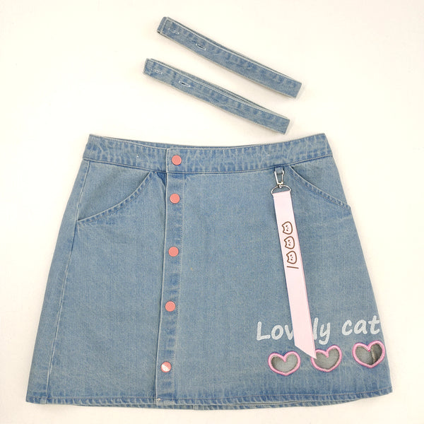 Close-up of button front design and detachable straps on cute denim pinafore skirt.