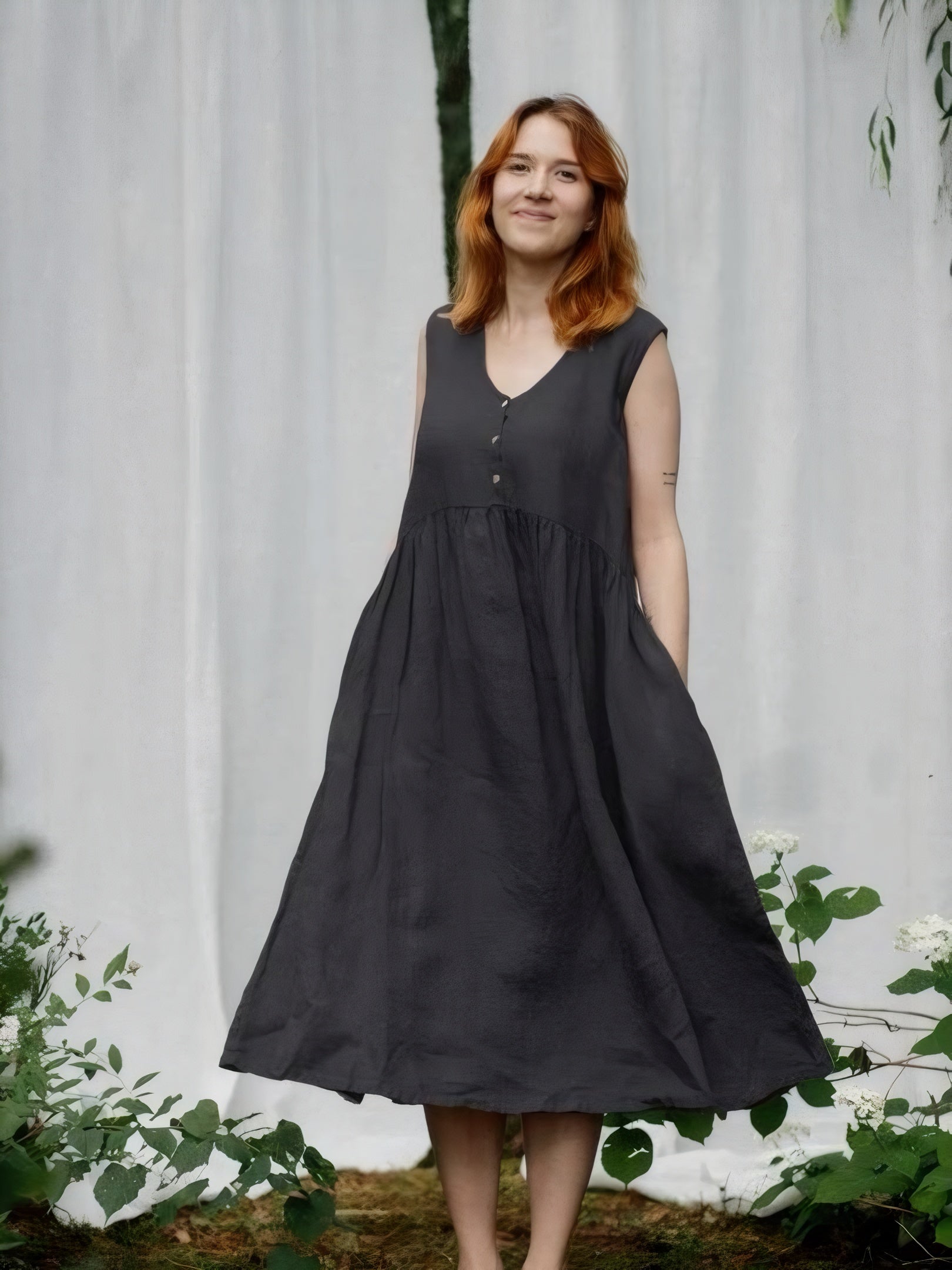 Woman in charcoal black linen sleeveless sundress smiling in garden