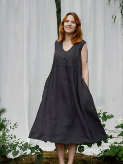 Woman in charcoal black linen sleeveless sundress smiling in garden