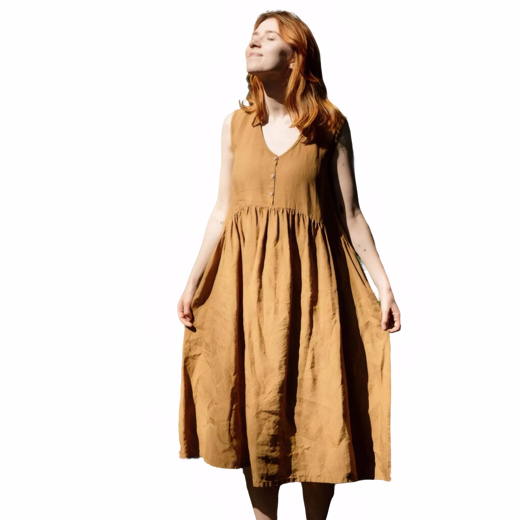 Woman wearing mustard yellow linen sleeveless dress standing in sunlight
